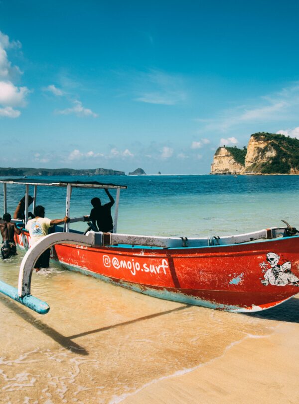 A colorful boat rests on a tranquil Bali beach, capturing the serene and picturesque coastal scenery.