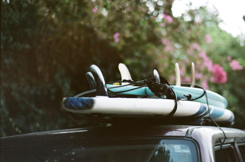 A stack of surfboards securely tied onto a car roof, ready for a summer adventure.