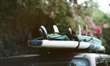 A stack of surfboards securely tied onto a car roof, ready for a summer adventure.