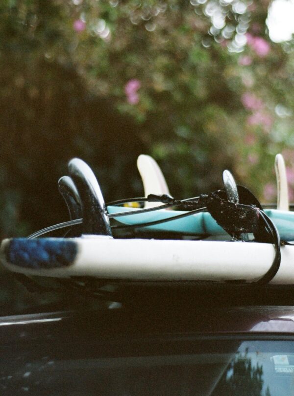 A stack of surfboards securely tied onto a car roof, ready for a summer adventure.